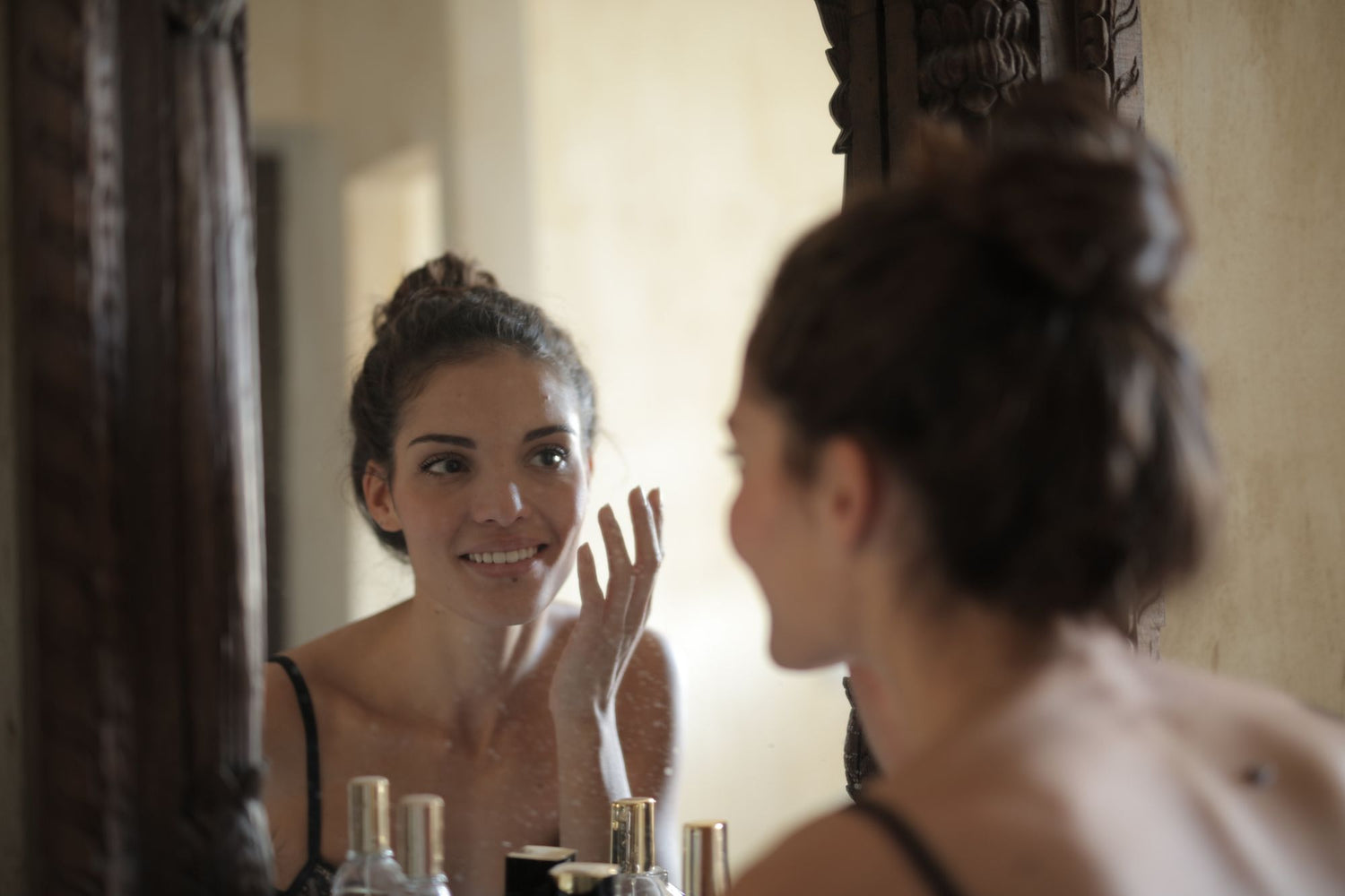 Mujer sonriendo frente al espejo, rutina de skincare